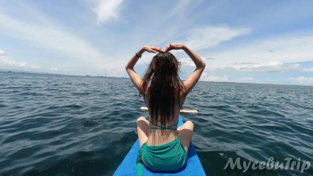 Woman making a heart pose on the bow of a private Bangka boat in Cebu