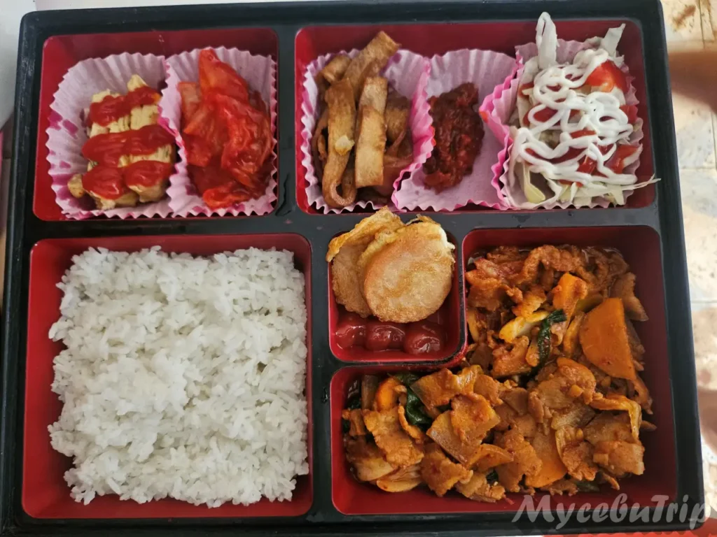 Spicy Stir-fried Pork (Jeyuk Bokkeum) lunch box with rice, kimchi, and fish cakes served on MyCebuTrip boat tours.