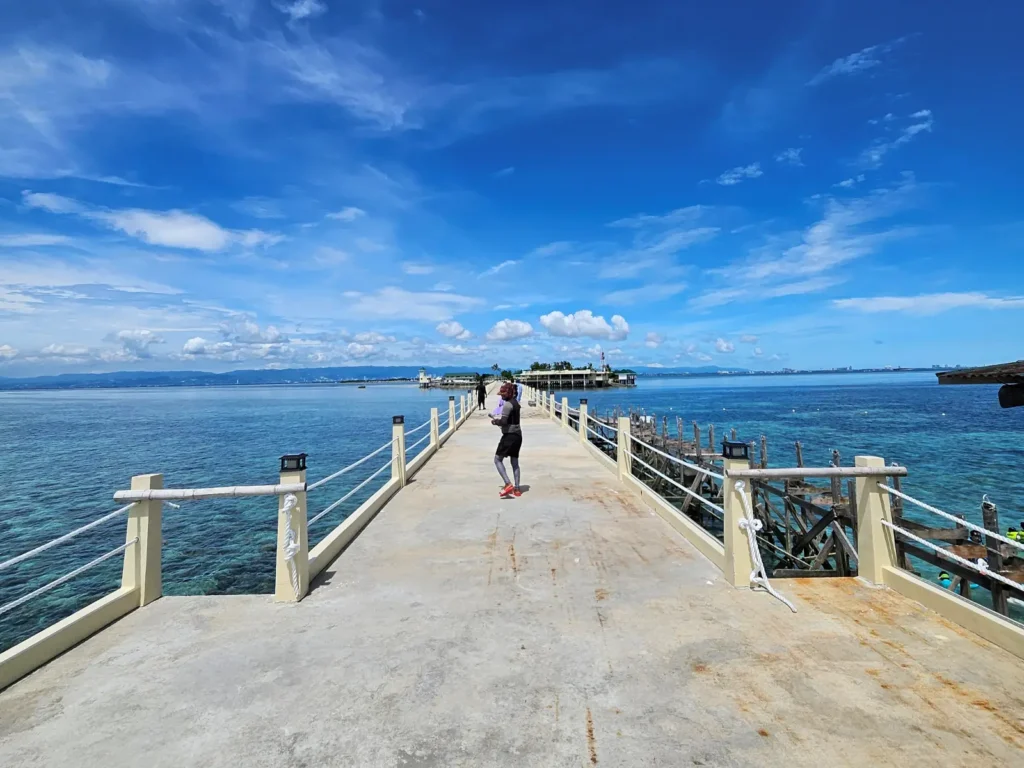 Woman walking on Nalusuan Island pier with blue sky