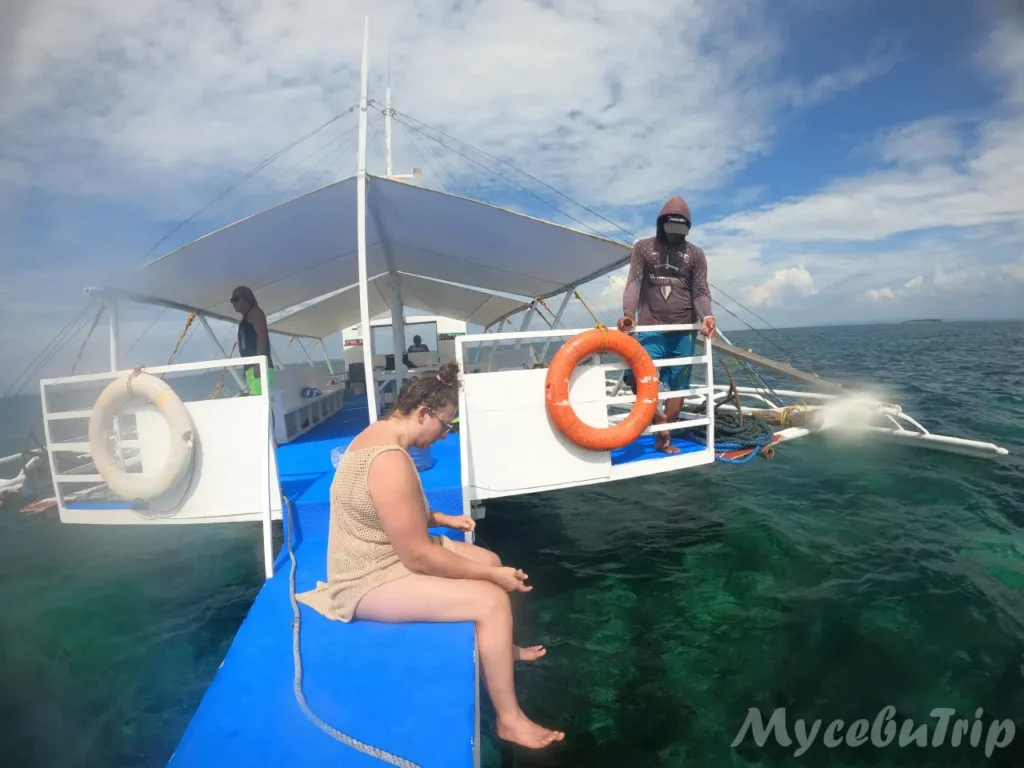 Traveler sitting on the bangka boat deck handline fishing during a Cebu island hopping tour